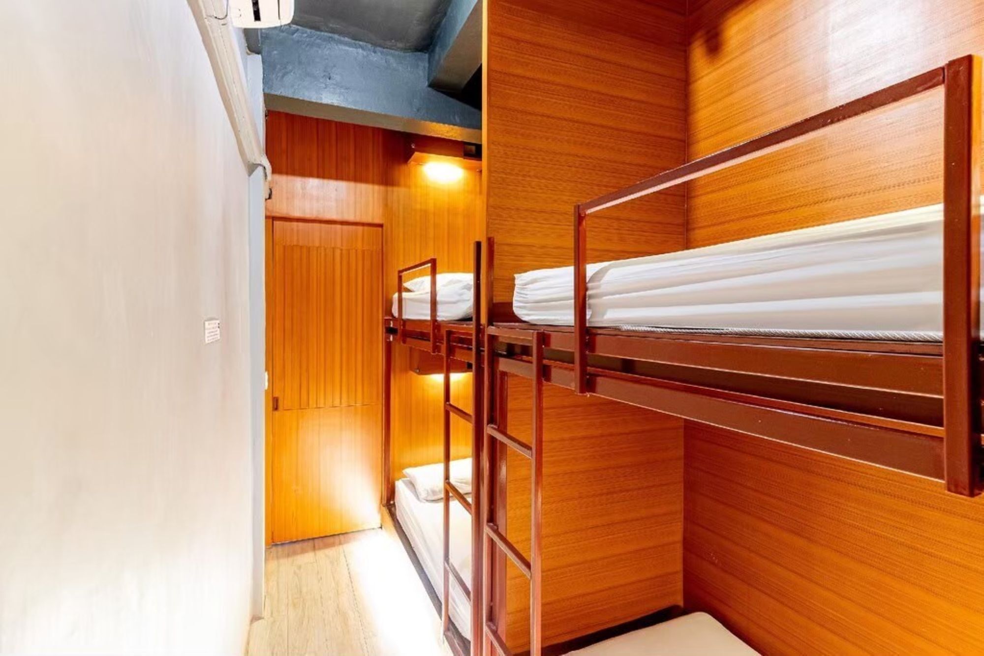 Una habitación pequeña con literas, paredes de madera y un ventanal.