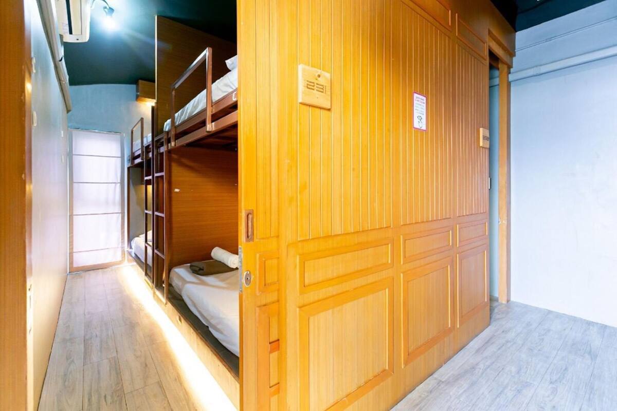 Una habitación con literas, un armario de madera y piso de tono claro.