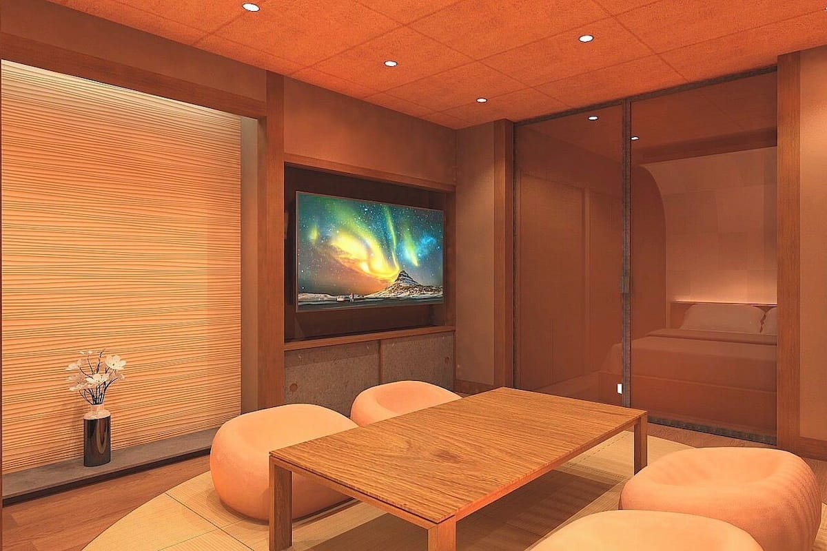 Quarto moderno com mesa de madeira, assentos acolchoados, televisão e porta de correr.