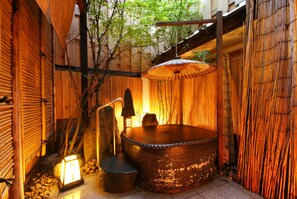 A traditional Japanese-style outdoor hot tub area with a wooden fence, bamboo elements, and a lantern. - Kinosaki Tajimaya (Toyooka)