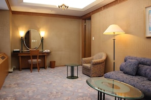 A hotel room with a desk, chair, round table, sofa, and a large mirror. - Keihanna Plaza Hotel (Seika)