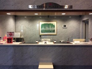 A reception desk at the Keihanna Plaza Hotel with a framed landscape painting above it.