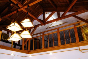 A high ceiling with wooden beams and hanging geometric light fixtures.