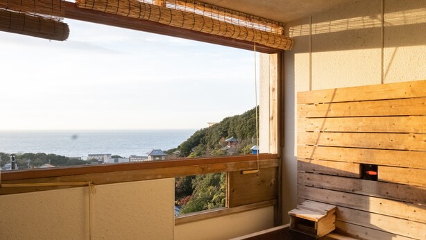 Uma sala de sauna com vista para o mar, bancos de madeira e uma pequena estrutura de madeira.