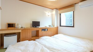 A hotel room with two beds, a desk with a computer, a small fridge, and a window with a view of buildings. - Business Hotel YANAGI Kitakyushu Kokura (Kitakyushu)