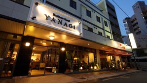 A business hotel named YANAGI with a modern facade, outdoor seating area, and visible entrance. - Business Hotel YANAGI Kitakyushu Kokura (Kitakyushu)