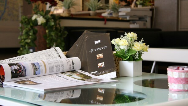 A brochure and a business card on a glass table with a vase of flowers and a candle. - Business Hotel YANAGI Kitakyushu Kokura (Kitakyushu)