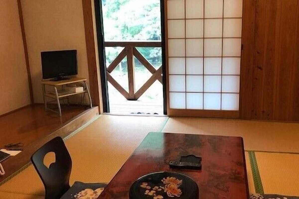 A traditional Japanese room with tatami flooring, a low table with a decorative plate, and a sliding door with a geometric pattern.