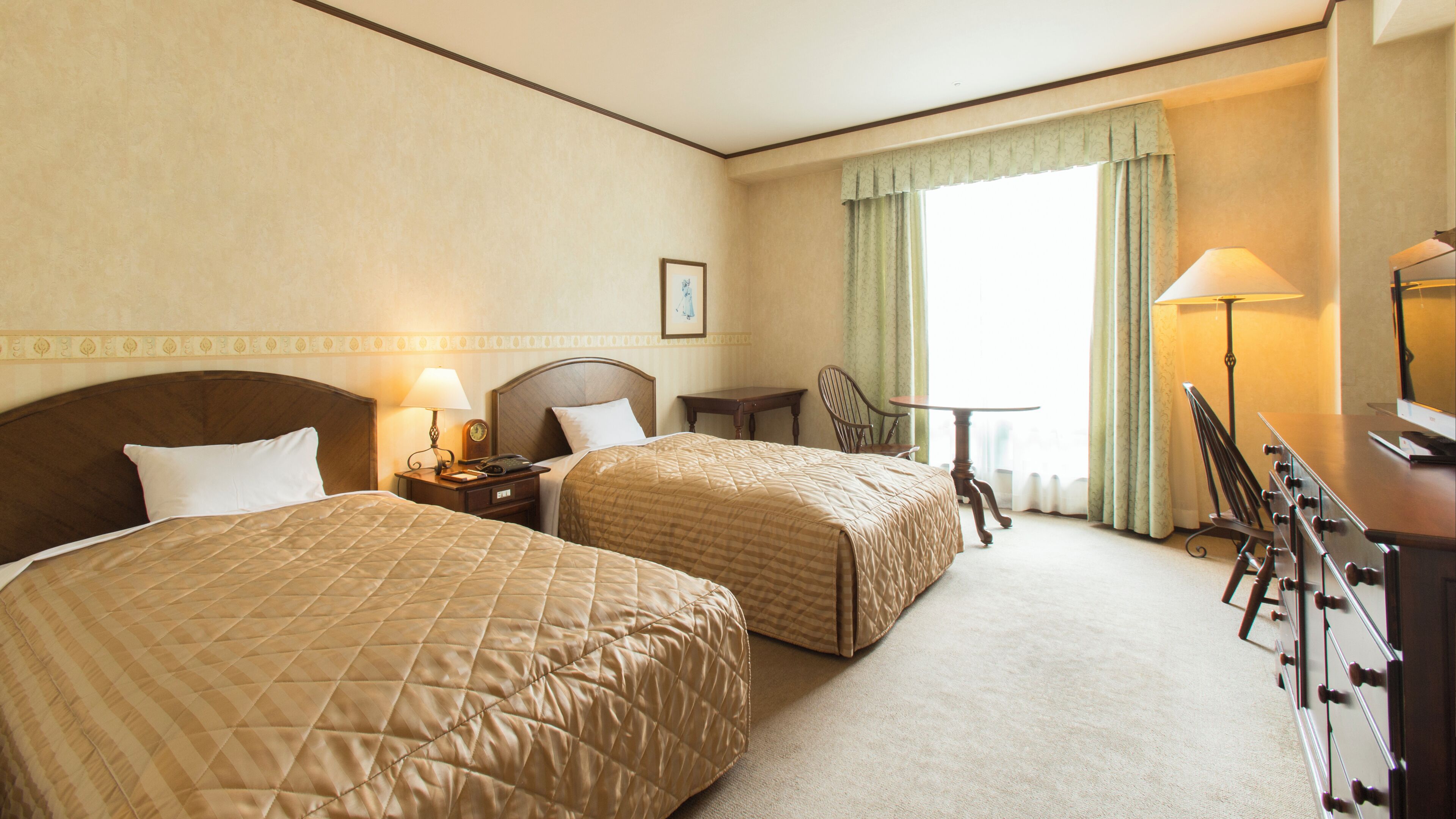 Quarto de hotel com duas camas, uma escrivaninha, uma cadeira, uma televisão e uma janela com cortinas.