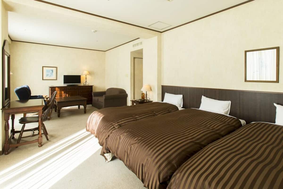Ein Hotelzimmer mit einem großen Bett, einem Schreibtisch mit Stuhl, einem Fernseher und einem Schminktisch.