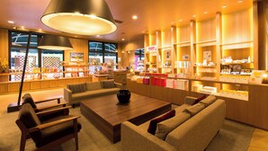 A modern interior with a seating area, a counter with various items, and a large window. - Kannabe Onsen Blue Ridge Hotel (TOYOKA SHI)