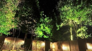 A nighttime outdoor area with a pool, wooden fences, and trees. - Kannabe Onsen Blue Ridge Hotel (TOYOKA SHI)
