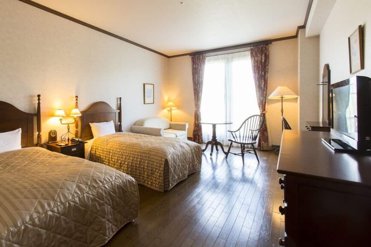 Habitación de hotel con dos camas, televisión, escritorio y una silla.
