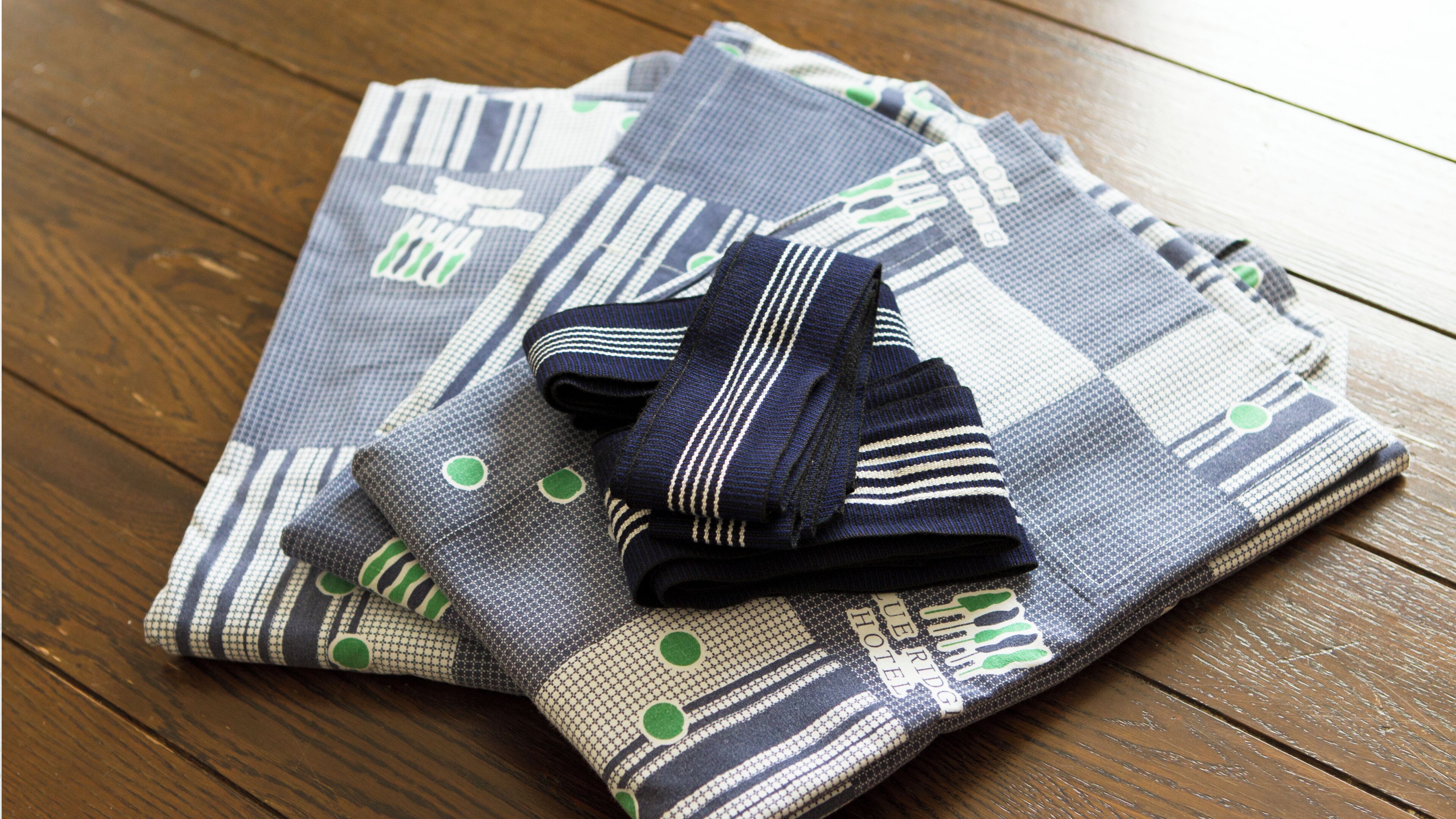 Ein gefaltetes Stück Stoff mit geometrischem Muster und ein Paar gestreifte Socken auf einer Holztischplatte.