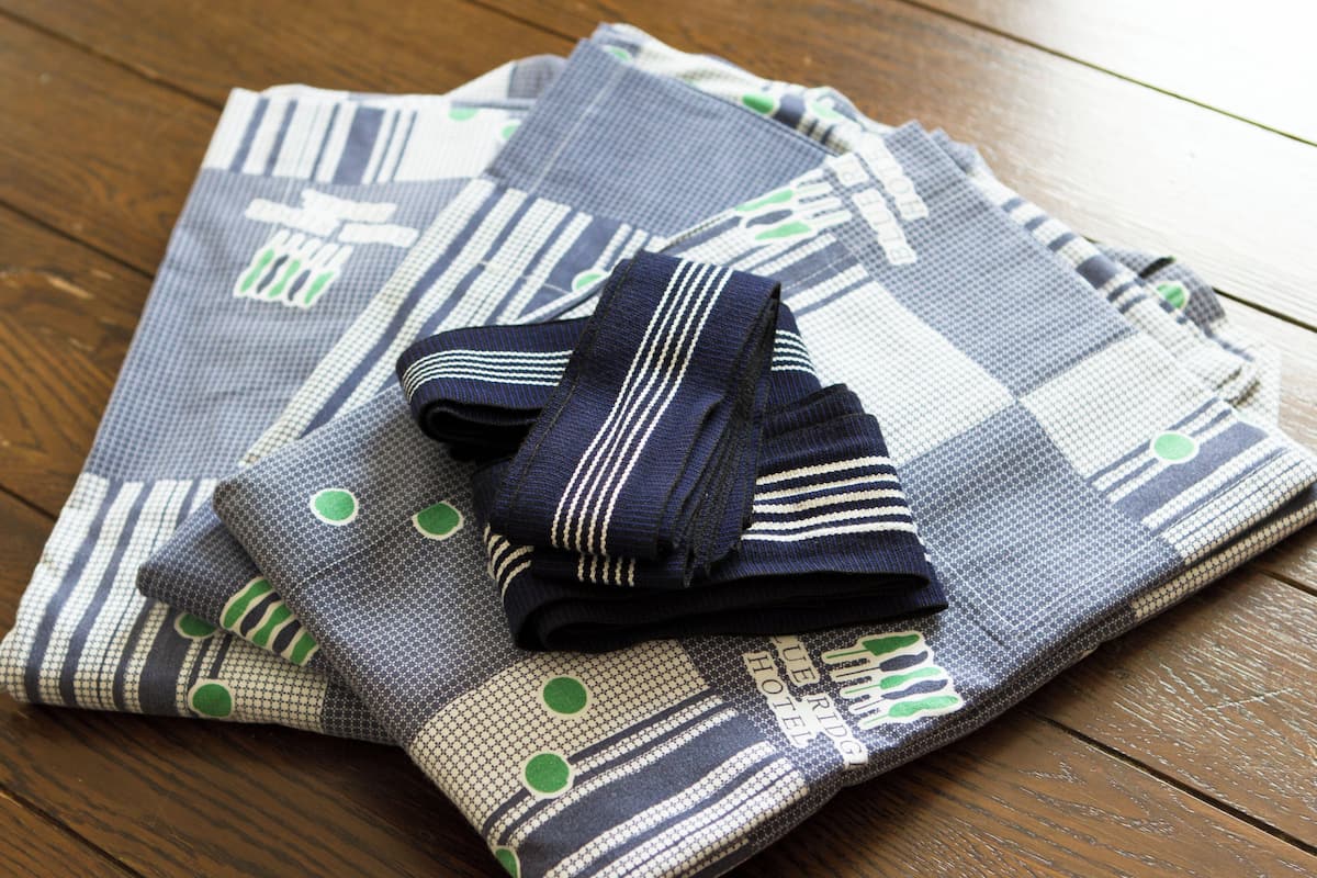 Ein gefaltetes Stück Stoff mit geometrischem Muster und ein Paar gestreifte Socken auf einer Holztischplatte.