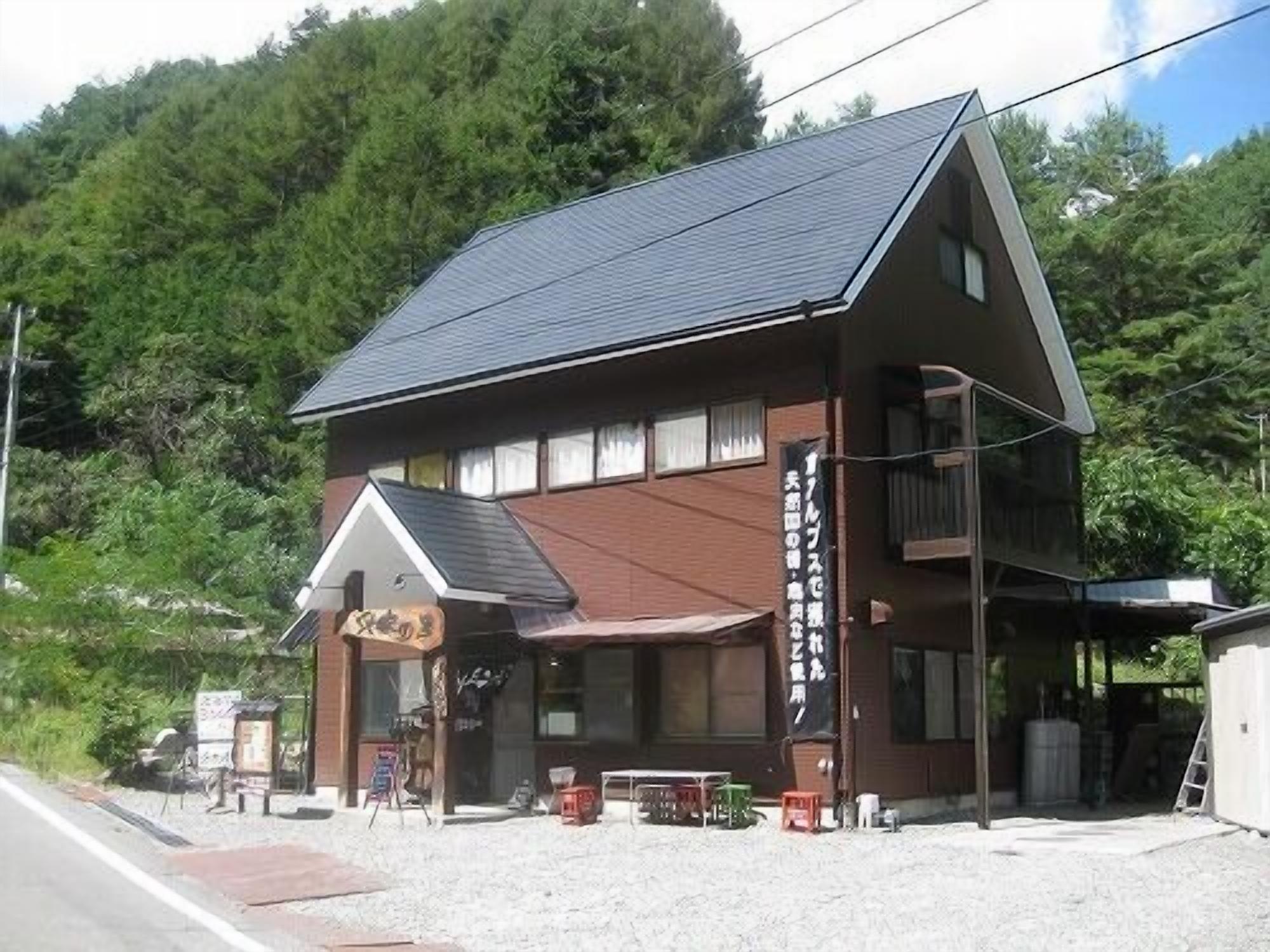 A two-story building with a sloped roof, a small porch area, and a visible sign.