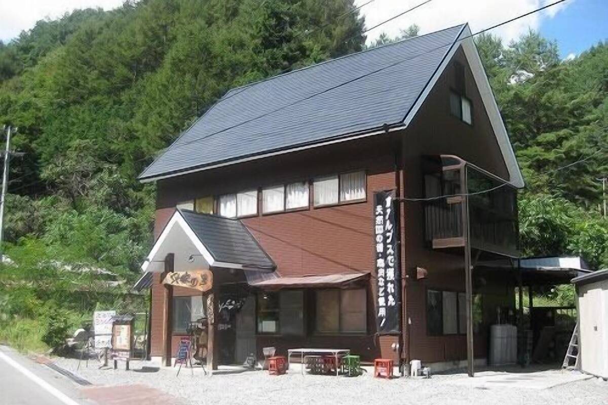 A two-story building with a sloped roof, a small porch area, and a visible sign.