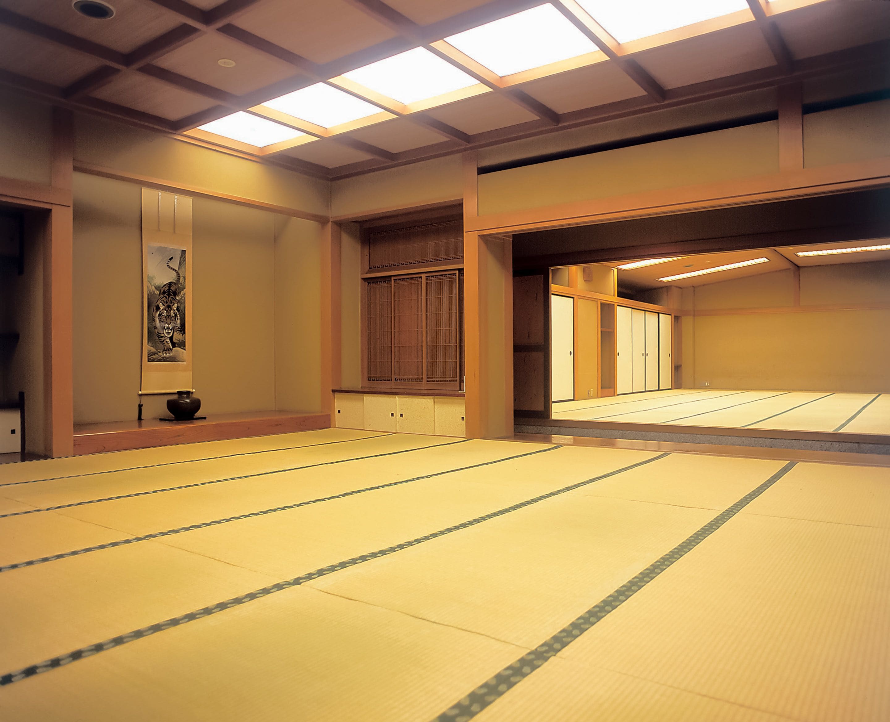 Una habitación con tatamis, puertas correderas, una obra de arte enmarcada y una estética japonesa tradicional.