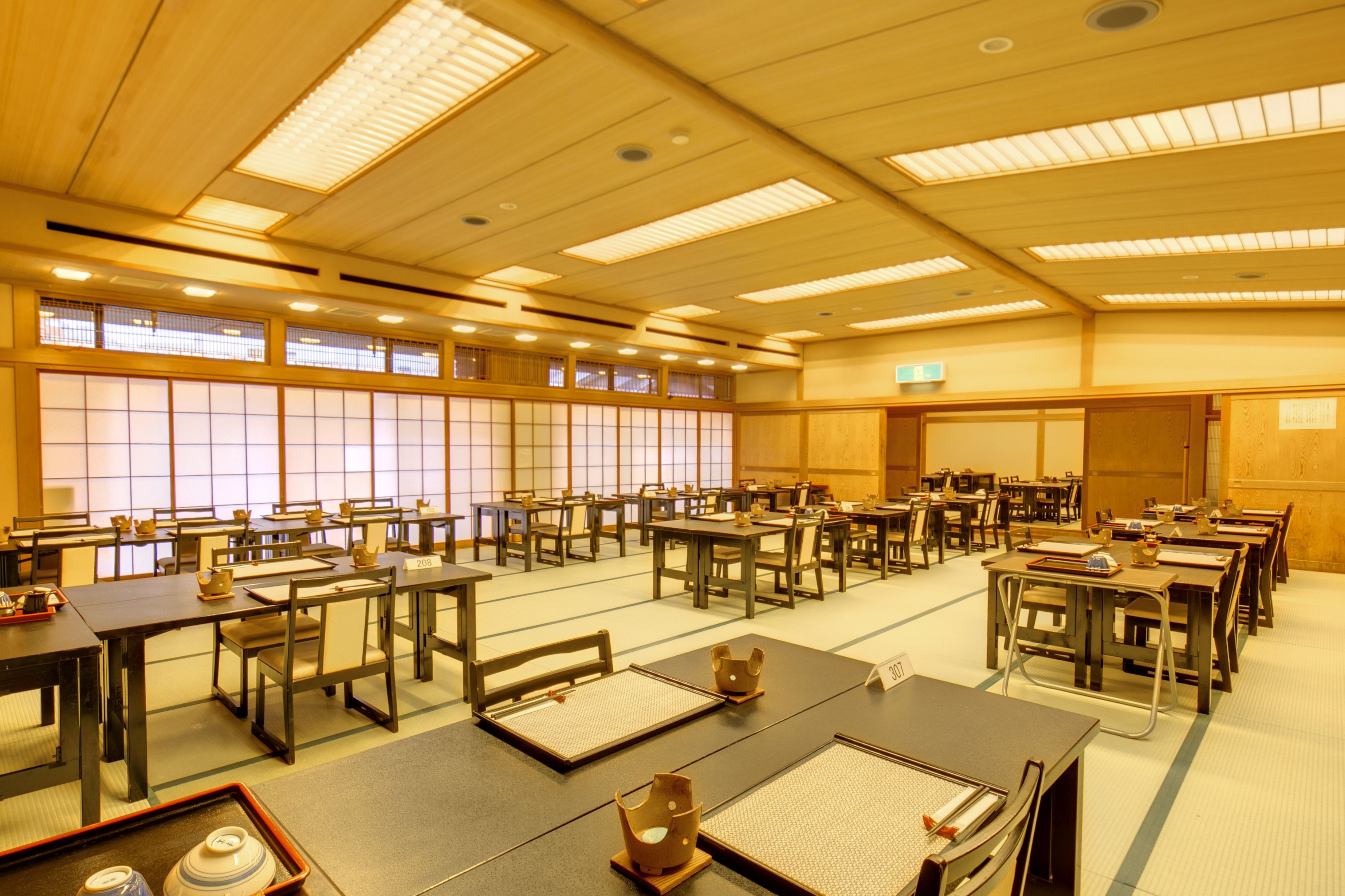 Ein Konferenzraum mit mehreren Tischen und Stühlen, großen Fenstern und traditioneller japanischer Gestaltung.