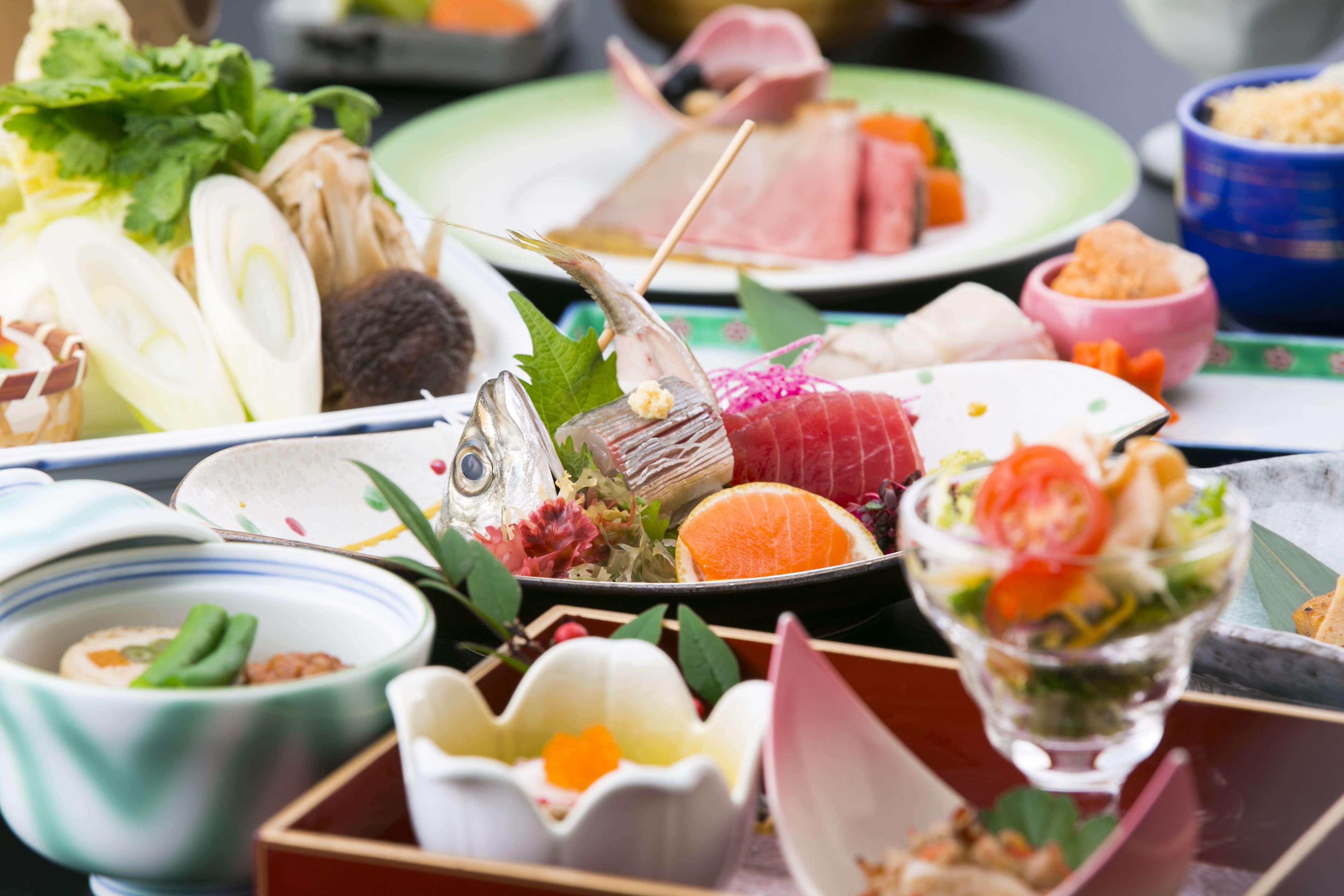 A variety of dishes including sashimi, vegetables, and a bowl of soup.