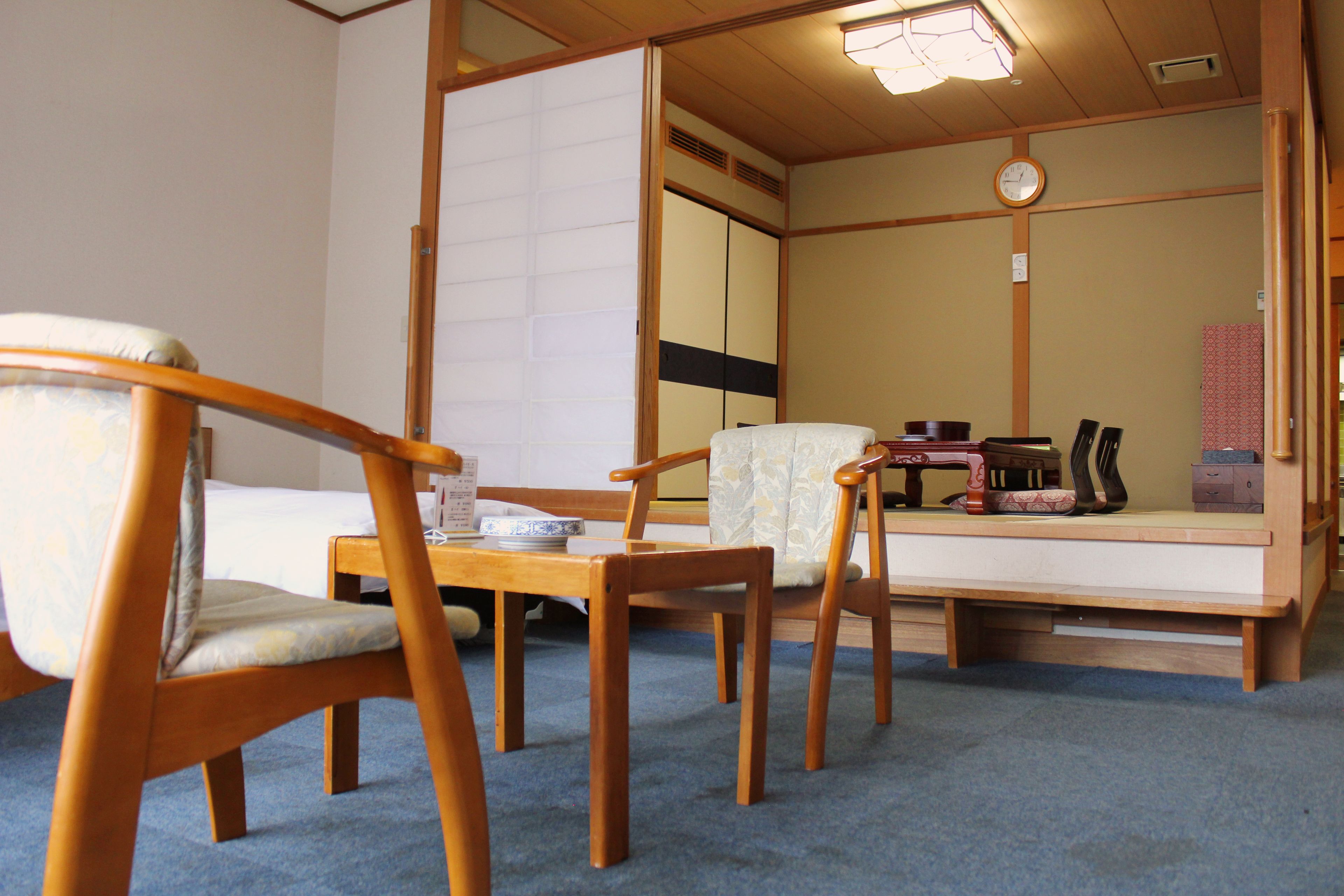 Une pièce de style japonais traditionnel, avec un sol recouvert de tatamis, une petite table basse avec un coussin et une porte coulissante.