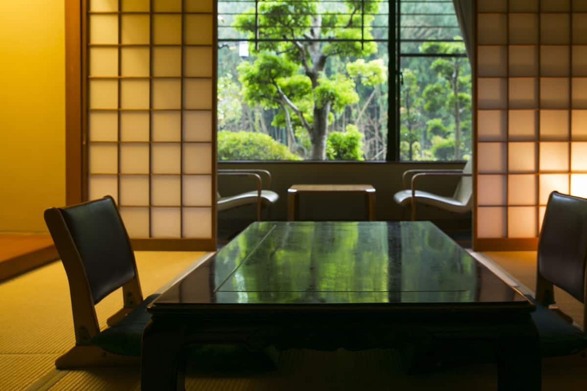 Una habitación japonesa tradicional con suelo de tatami, una mesa baja y paneles shoji.