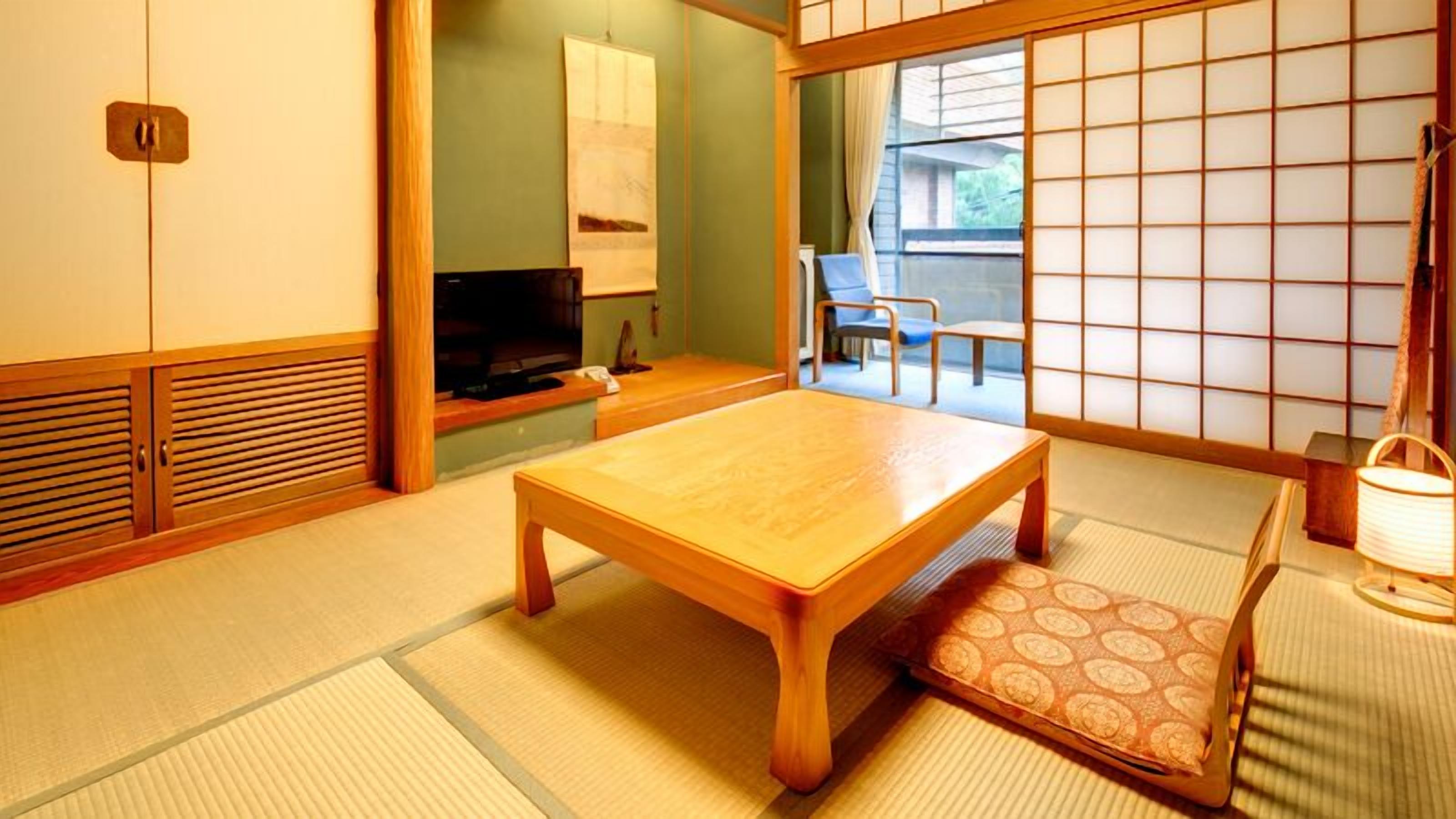 A traditional Japanese room with tatami flooring, a low wooden table, a television, and sliding doors.