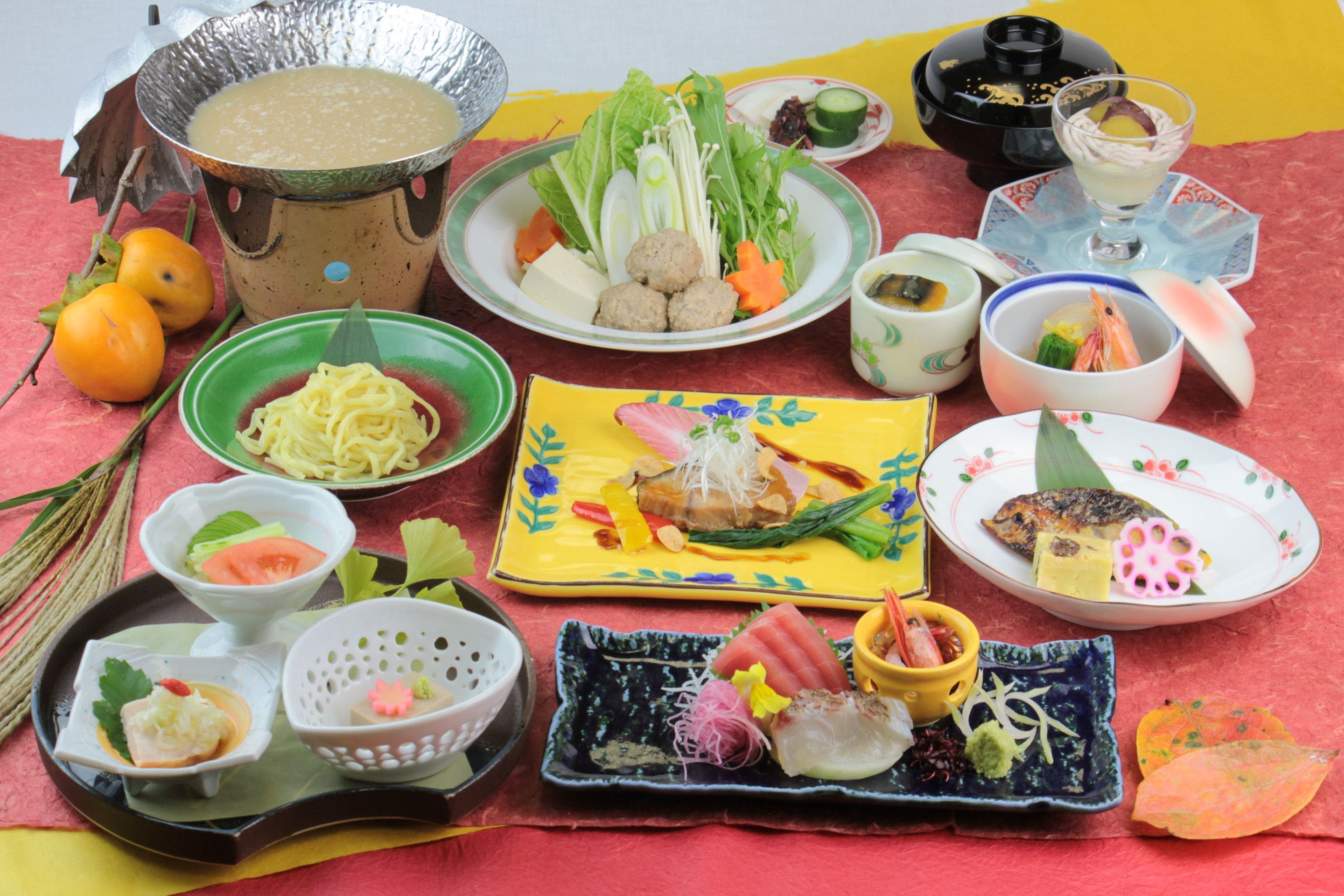 A variety of dishes and food items arranged on a table, including a bowl of soup, plates with vegetables, and other food preparations.