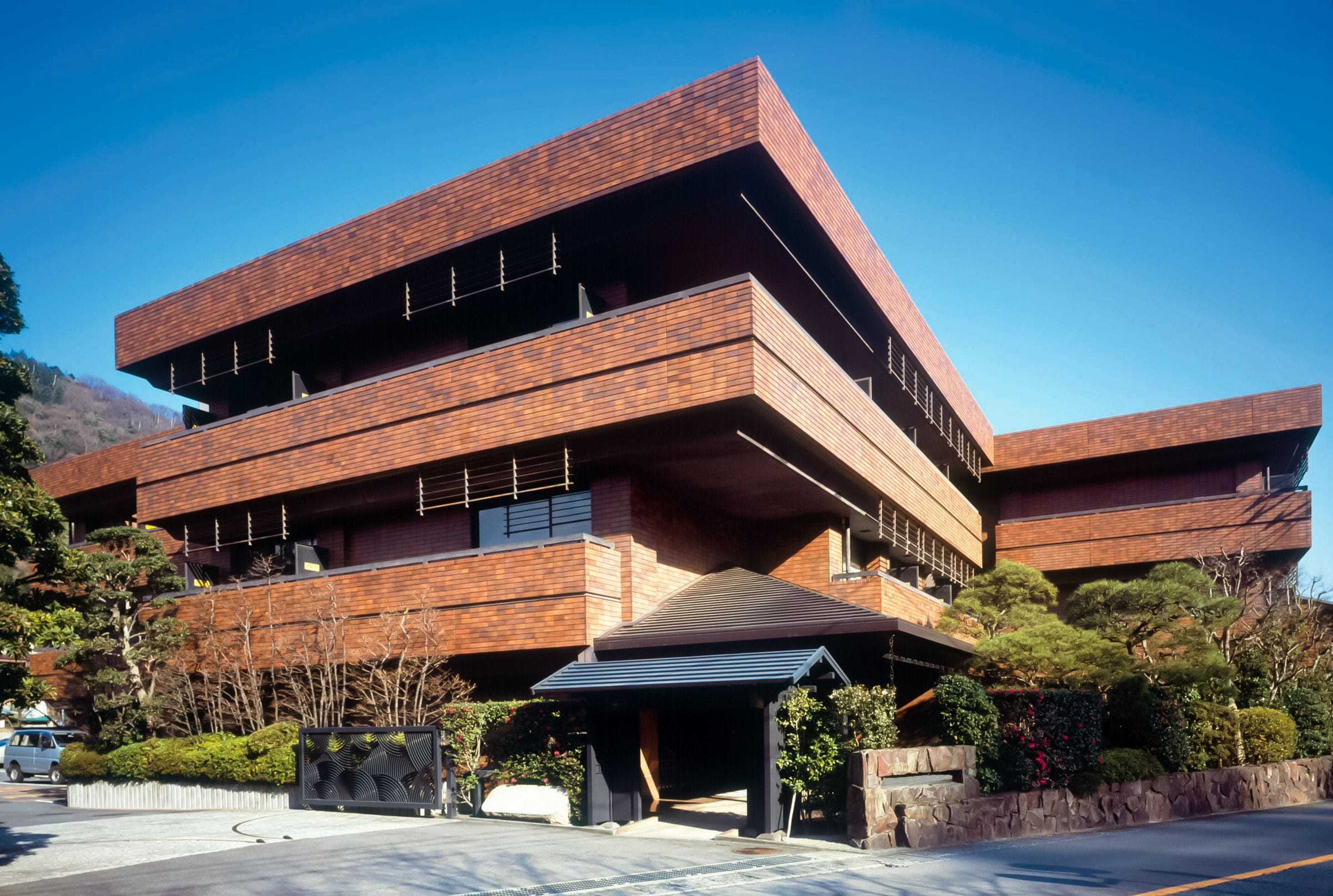 Un edificio de varios pisos con un diseño arquitectónico moderno, que destaca por un voladizo prominente y un acceso cubierto.