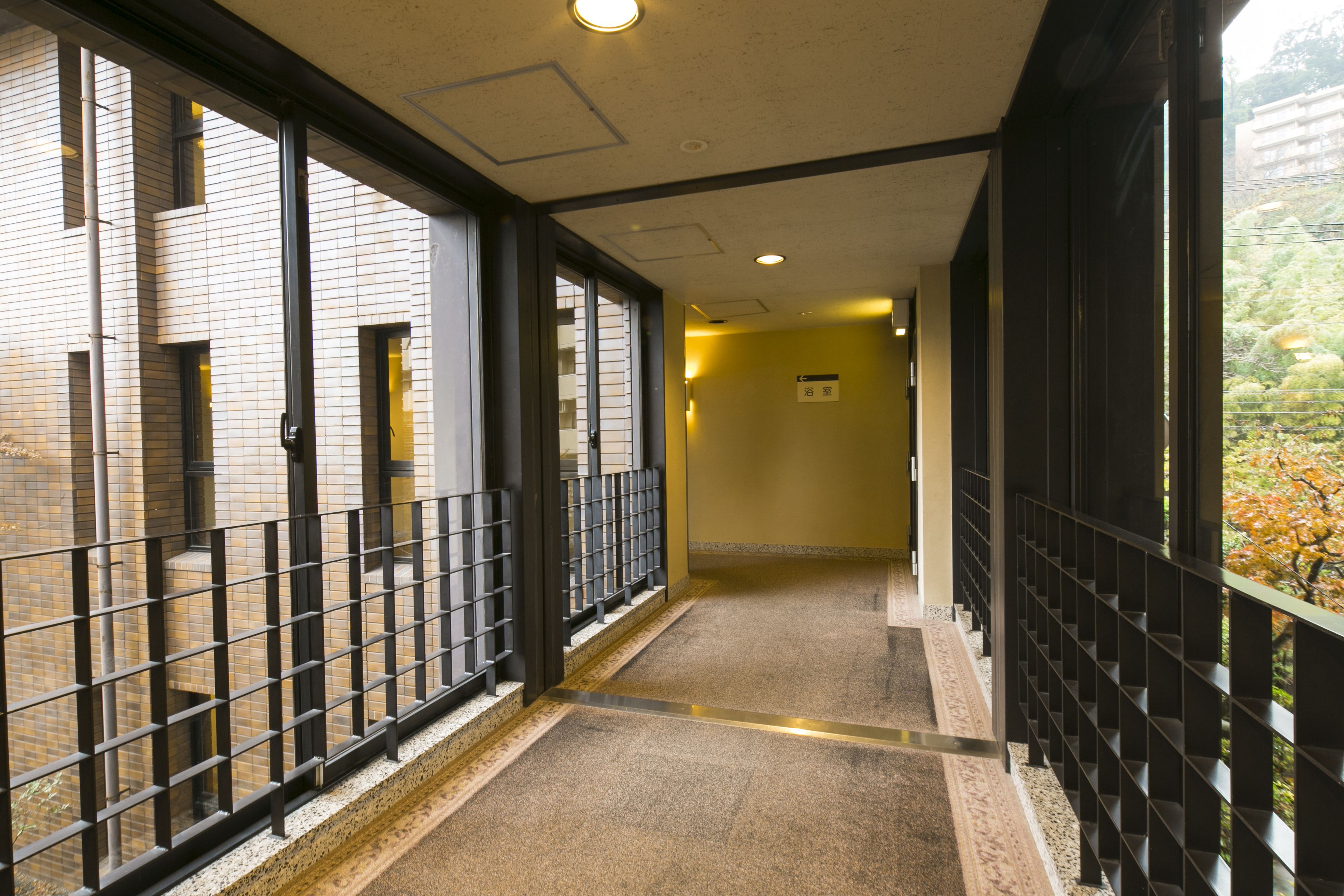 A corridor with a tiled floor, metal railings, and a view of a building with windows.