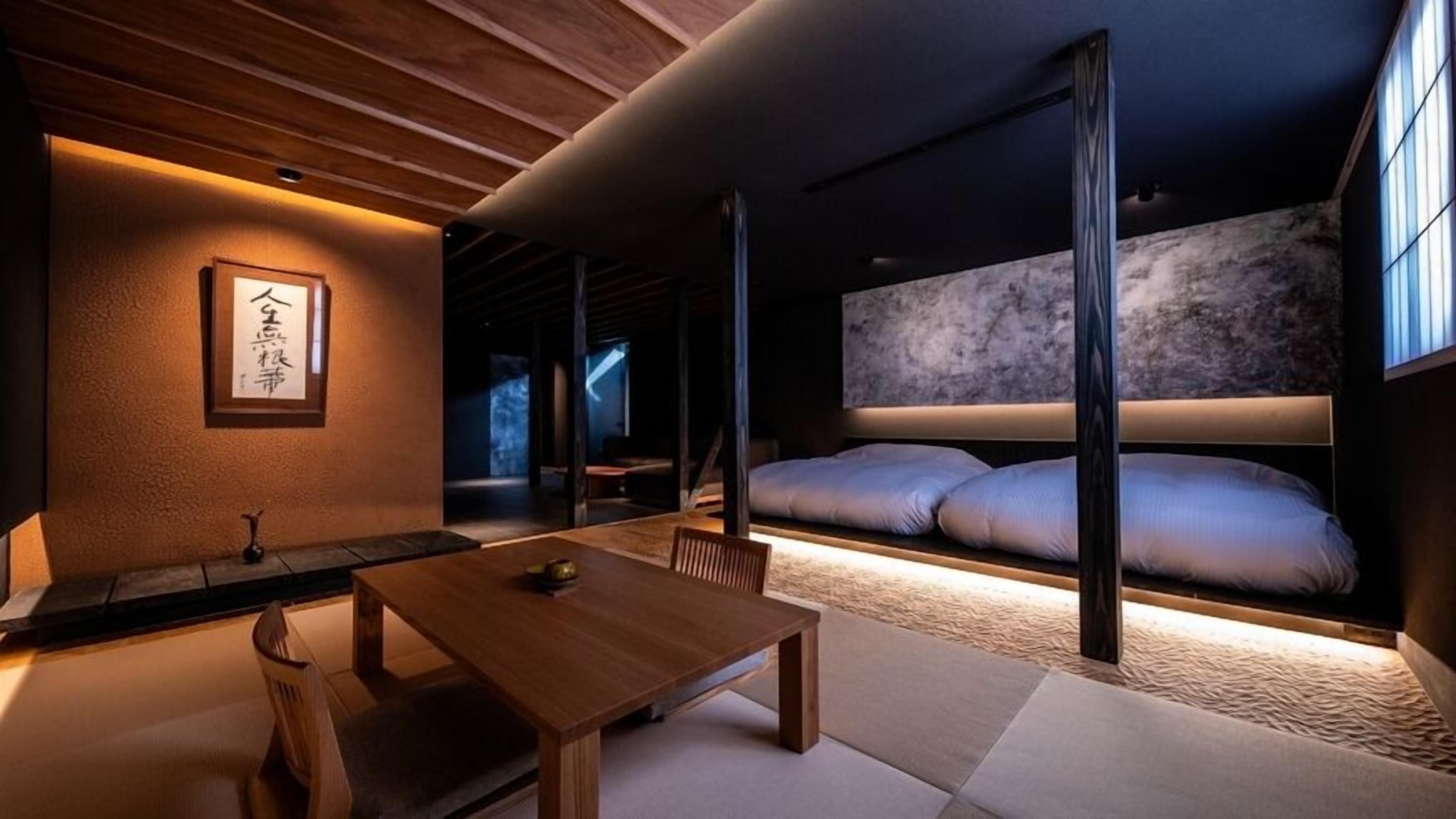 A traditional Japanese room with tatami flooring, a low wooden table, and a futon bed.