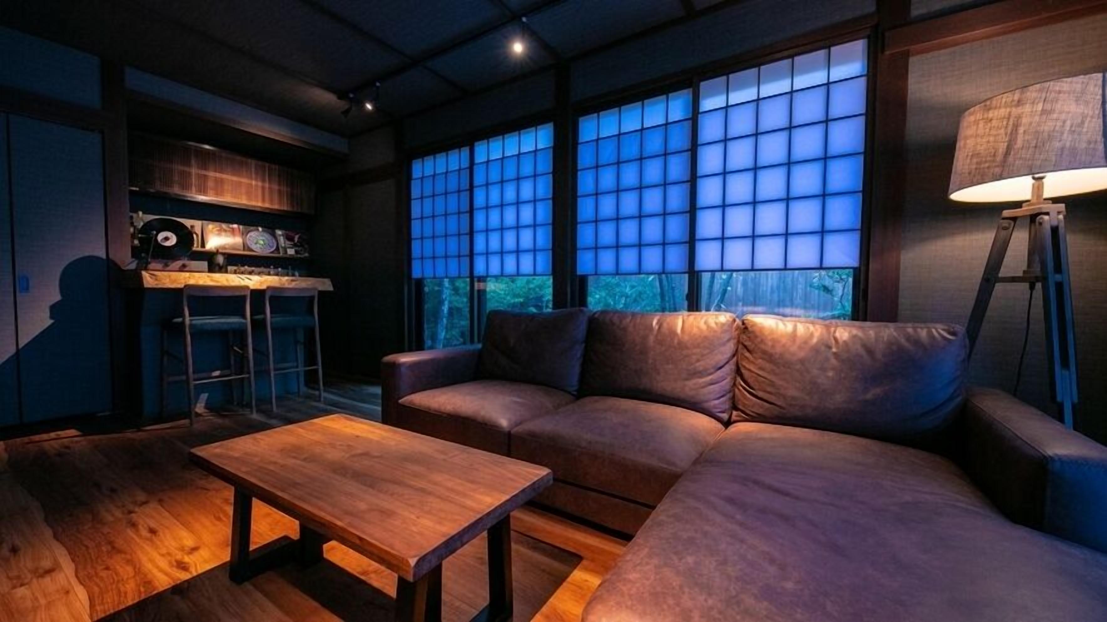 A modern living room with a sofa, a coffee table, and a bar area with a record player.