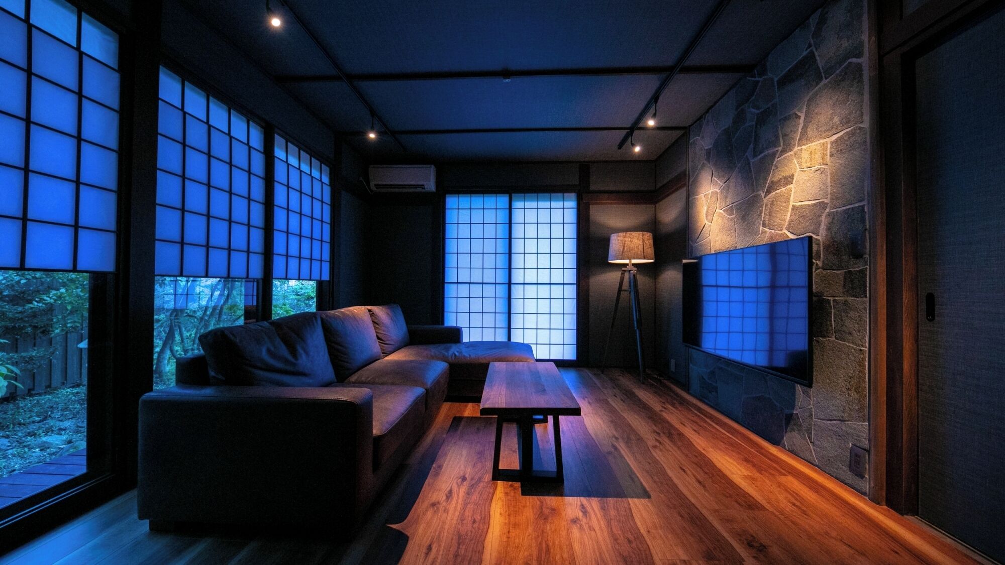 A modern interior with a sofa, a table, and large windows.