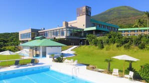 Hotel moderno com piscina, área de estar externa e vista para uma montanha.