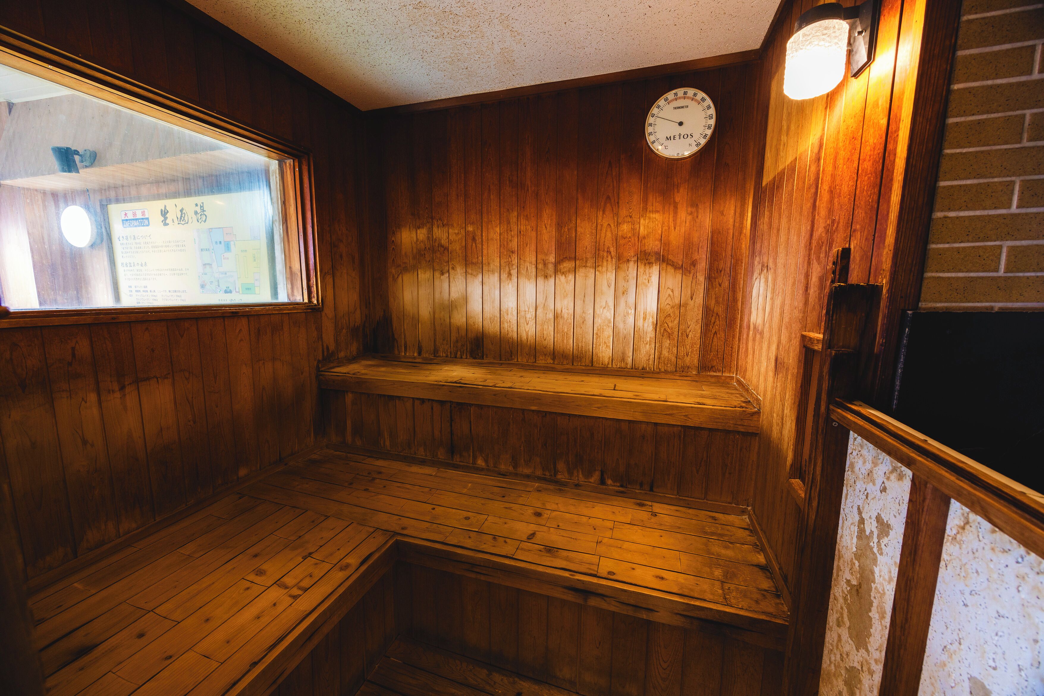 A wooden interior with a bench, a clock, and a window.