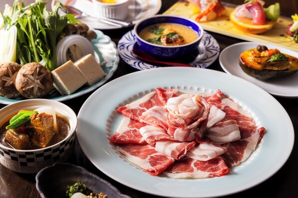 A variety of dishes including sliced meat, vegetables, and a bowl of soup on a table.