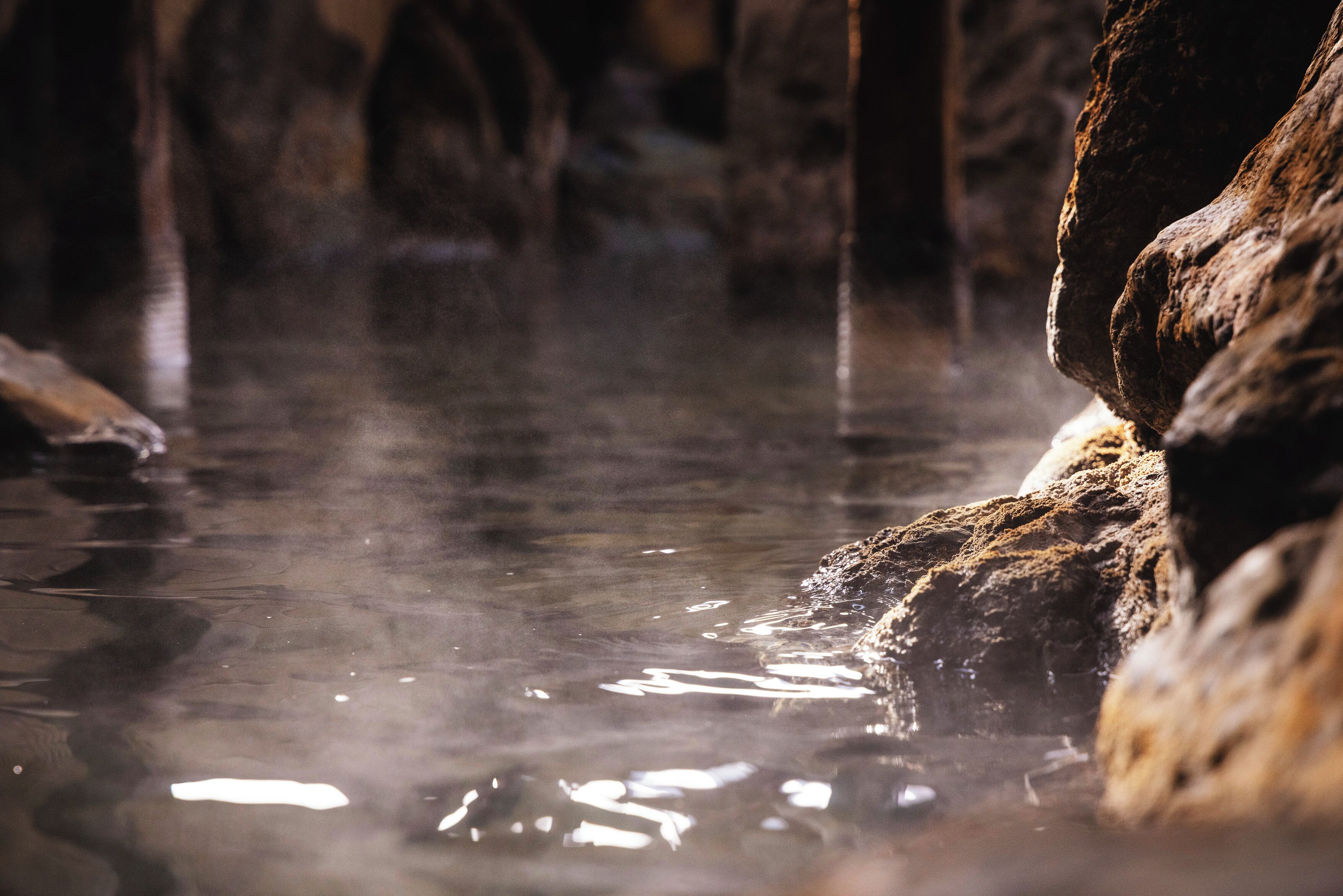 A natural hot spring with clear water and rocky formations.