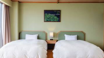 Una habitación con dos camas, una mesita de noche con lámpara, un cuadro en la pared y suelo de madera.