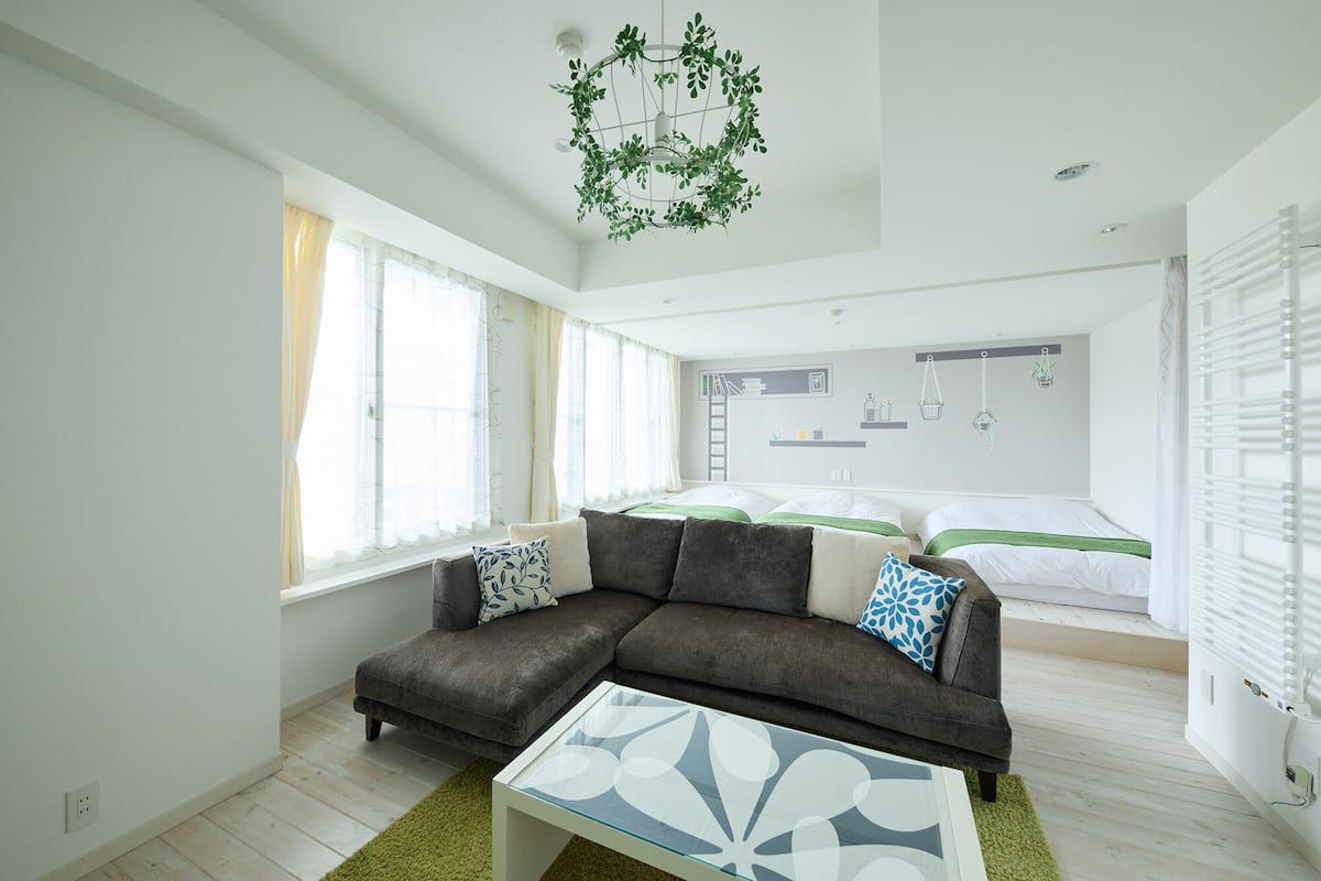 A modern living room with a sofa, a glass coffee table, and a hanging plant.