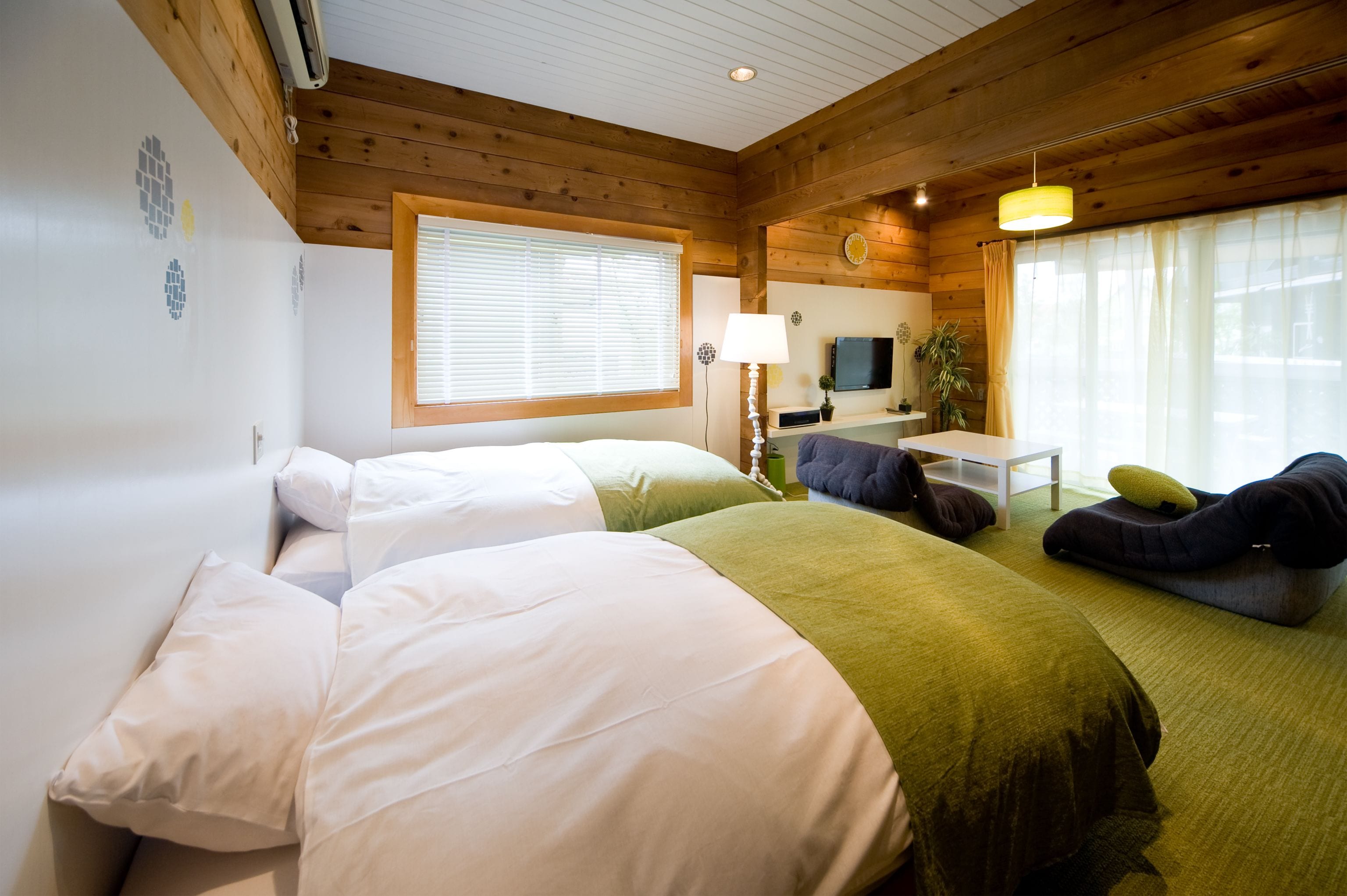 A room with two beds, a desk, a TV, and a window with curtains.