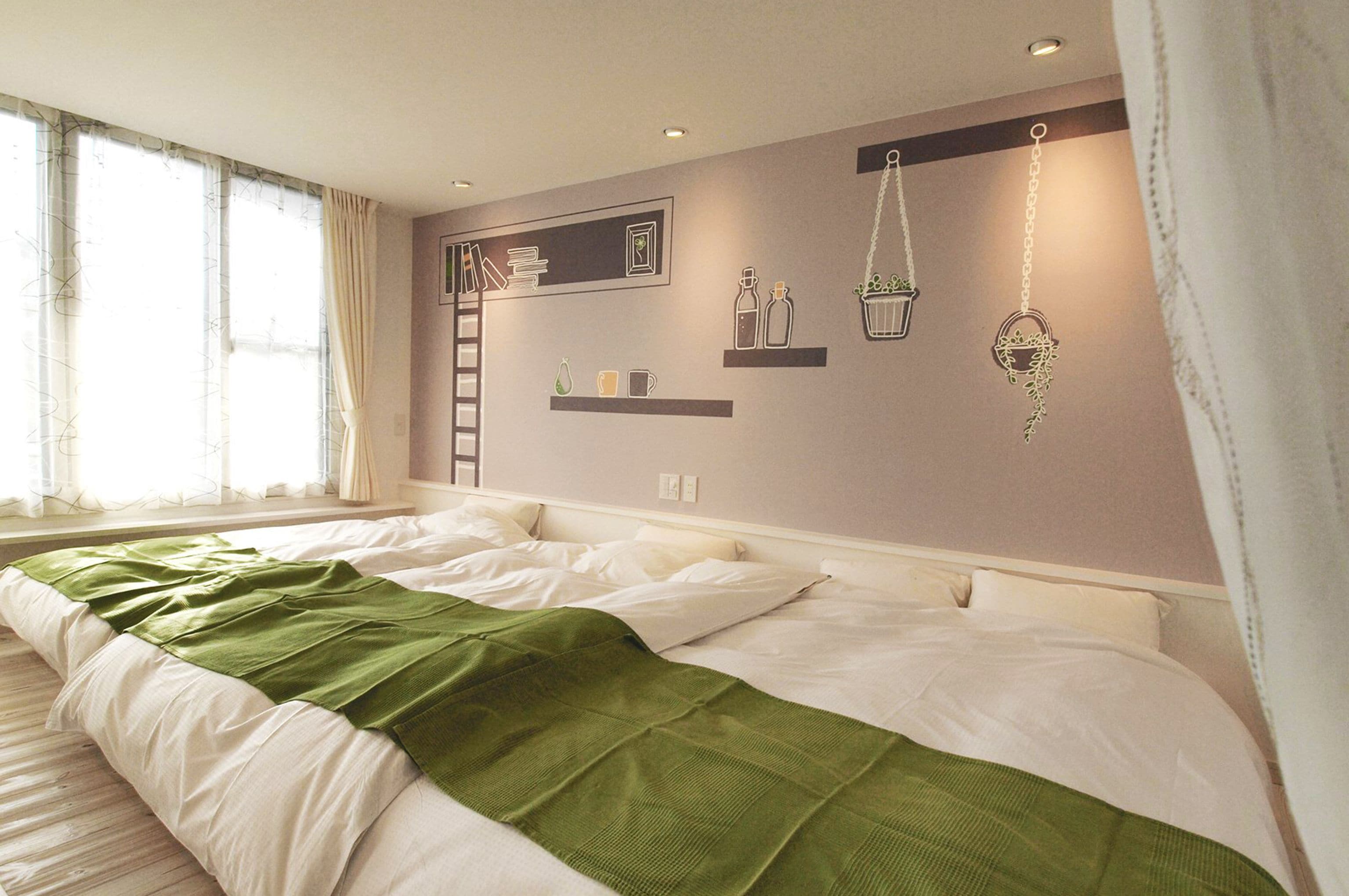 A bedroom with a large bed, a window with curtains, and wall-mounted shelves with decorative items.