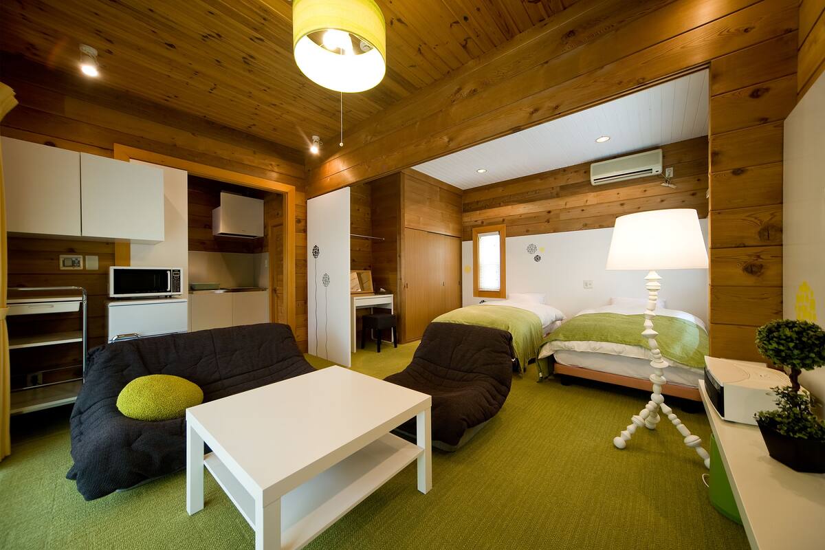 A compact room with a kitchenette, a bed, a desk, and a sofa.