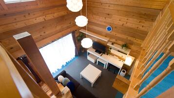 A wooden cabin interior with a dining area, kitchen, and living room.