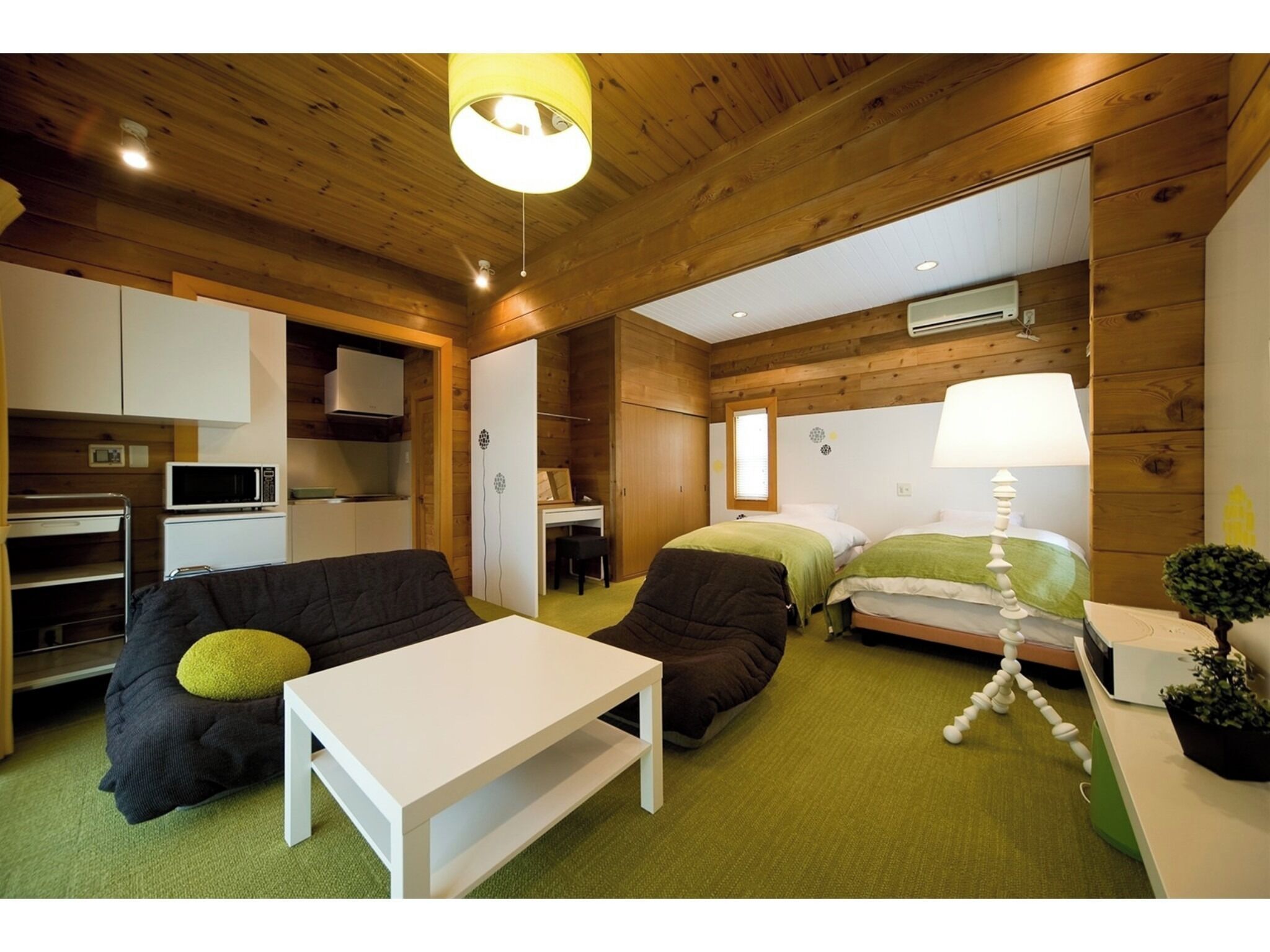 A compact room with a kitchenette, a bed, a sofa, and a small table.