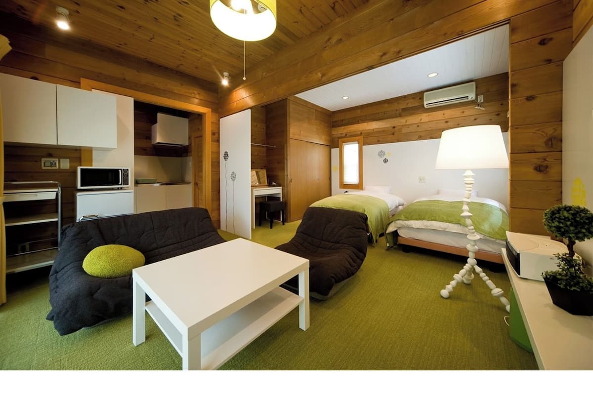 A compact room with a kitchenette, a bed, a sofa, and a small table.
