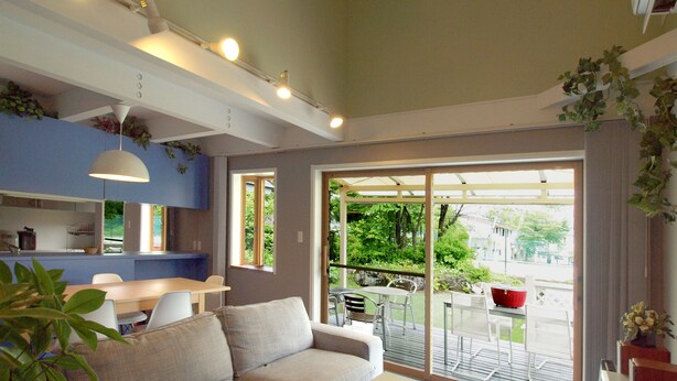 Een moderne woonkamer met een bank, een eettafel en stoelen. Er is een schuifdeur naar een buiten terras.