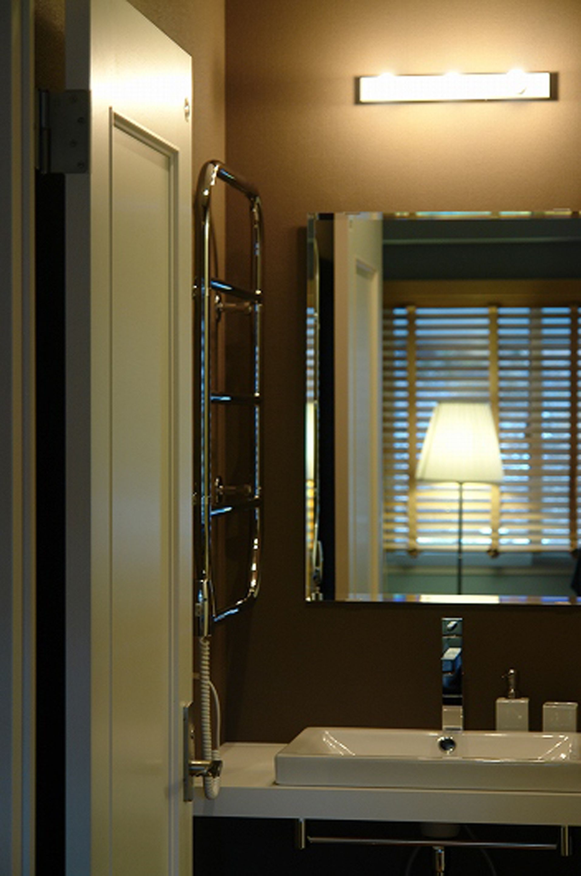 A bathroom with a white sink, a mirror, and a towel rack.
