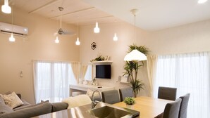 Een moderne keuken met een centraal eiland, roestvrijstalen apparatuur en een eethoek met een houten tafel en stoelen.