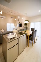 Una cocina moderna con una isla central, electrodomésticos de acero inoxidable y un comedor con mesa y sillas de madera.