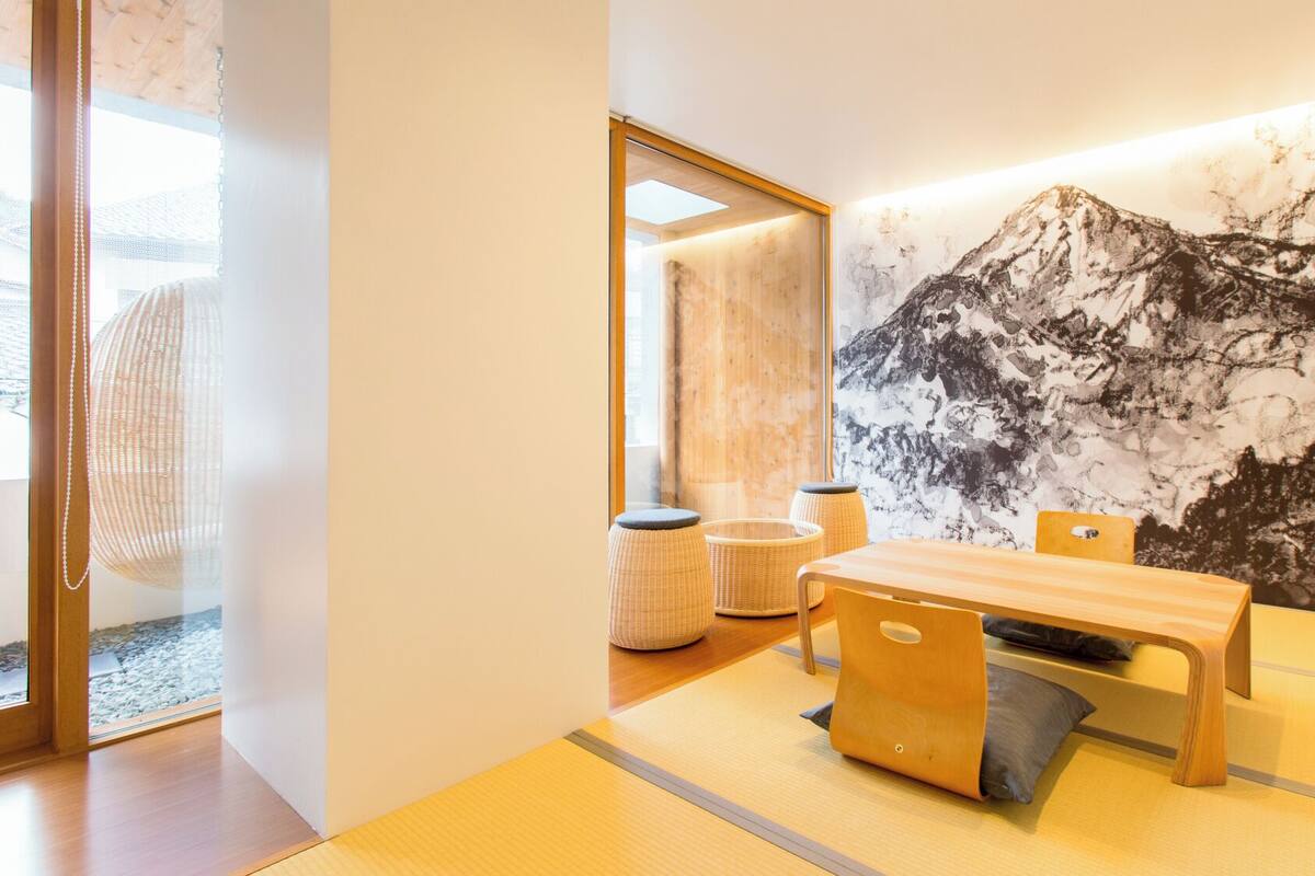 Een modern interieur met een houten tafel, stoelen en een groot muurschilderij.